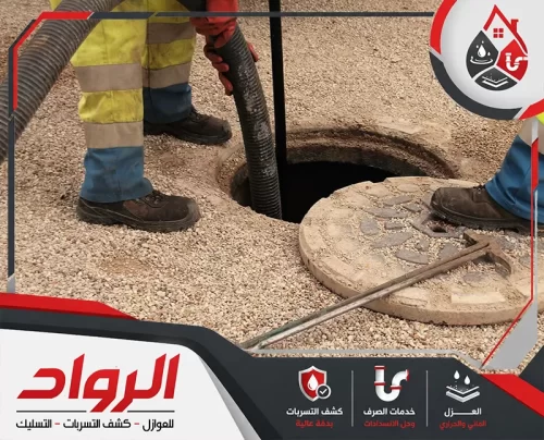عاملين يتعاملان مع فتحة صرف أرضية مفتوحة، مع استخدام خرطوم شفط كبير لسحب المياه أو المخلفات من داخل البيارة، ما يعبر عن أعمال شفط البيارات وتنظيف غرف التفتيش ومعالجة تجمعات الصرف.